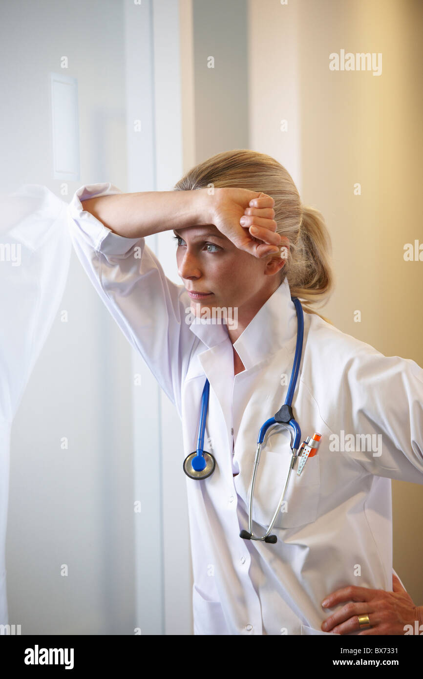 Doctor against a window, thinking Stock Photo