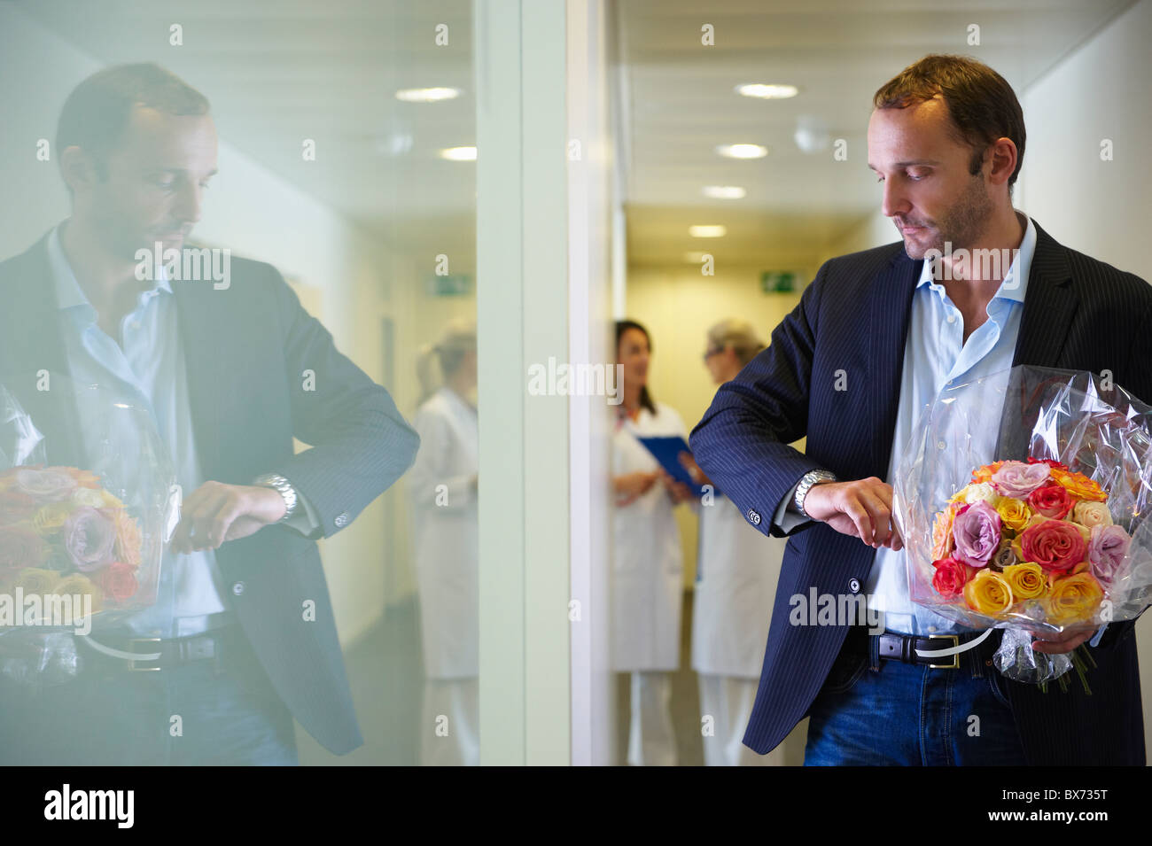 Man with flowers, looking at his watch Stock Photo