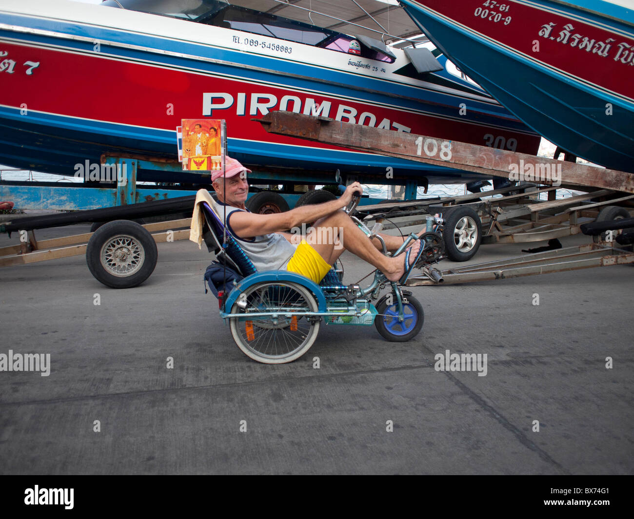 The old man riding his tricycle bicycle along Pattaya Bay Stock Photo