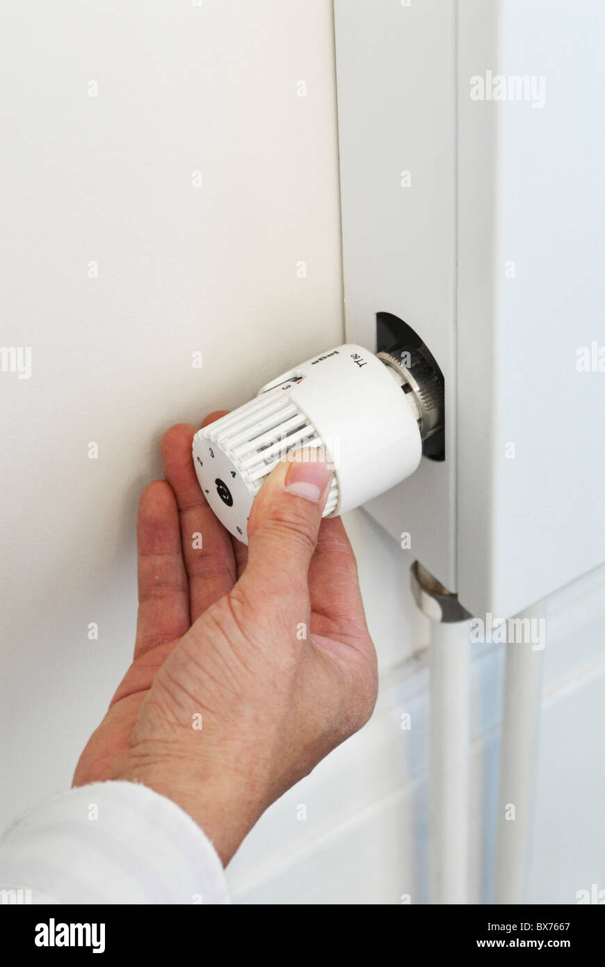 Man adjusting thermostat on radiator Stock Photo