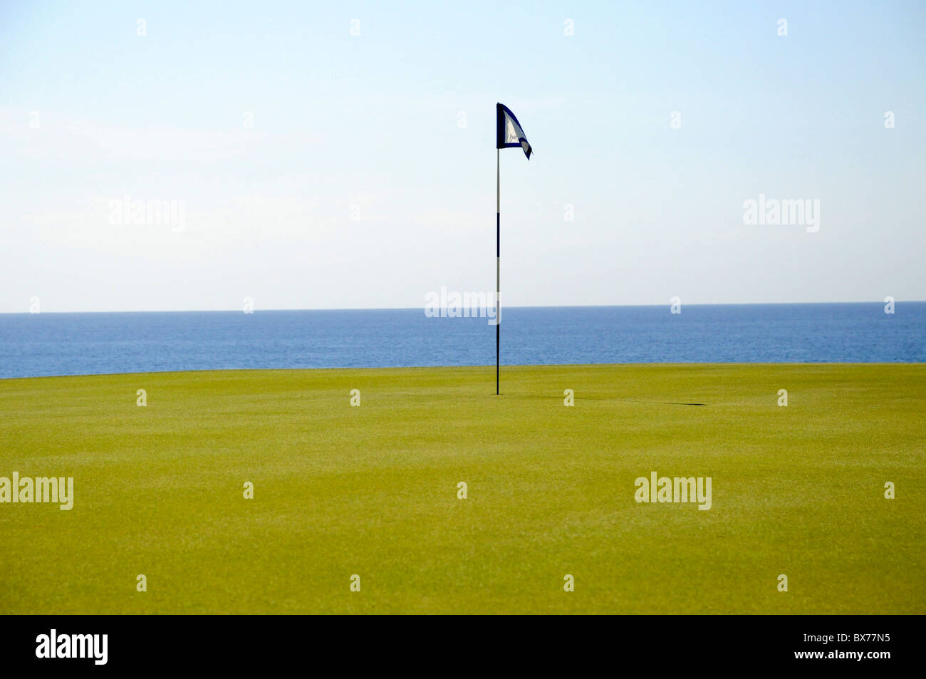Putting green and flag pole on 14th hole at Puerto Los Cabos Golf Club in San Jose del Cabo, Mexico Stock Photo