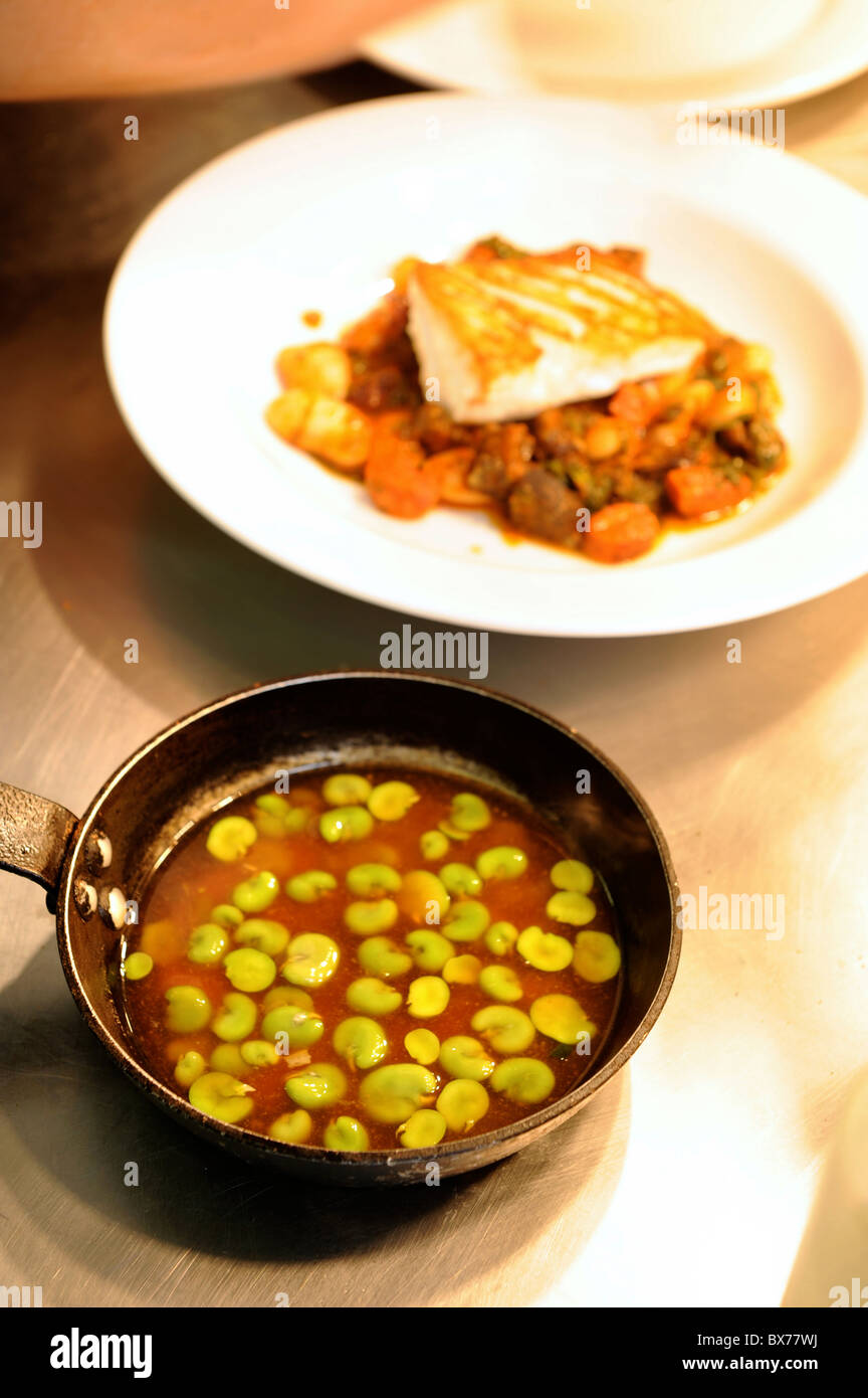 A sauce of peeled broad beans in preparation and a white fish main