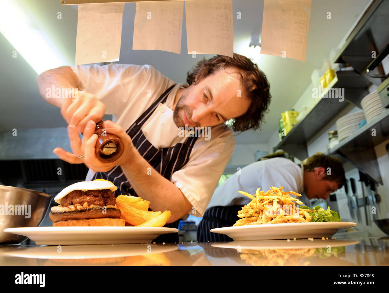 The Chef Stephen Terry adds seasoning to a burger and fries meal at The Hardwick near Abergavenny 2008 Stock Photo