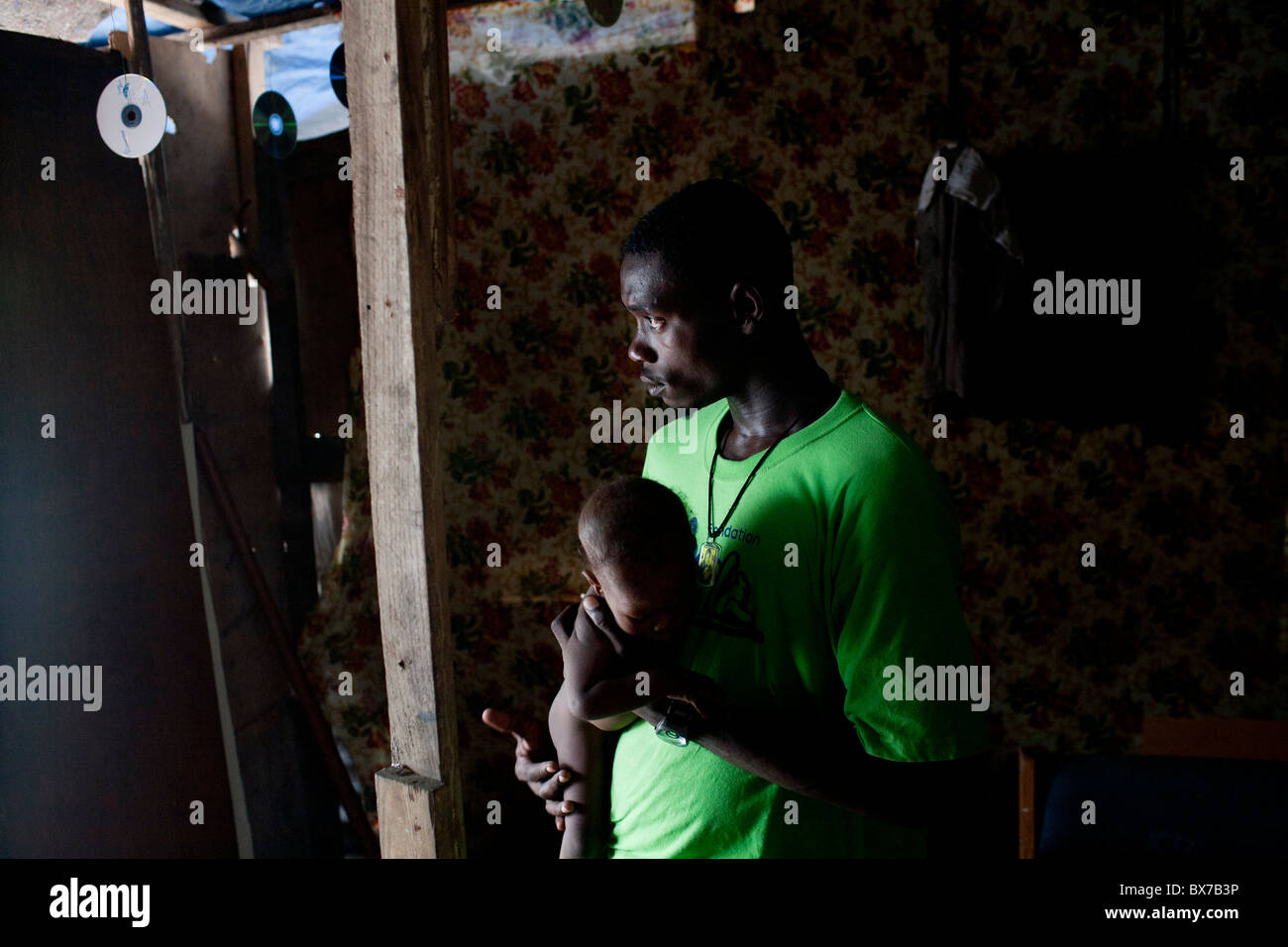 A man holds a friend's baby in the camp for people displaced by the earthquake on Champs de Mars Stock Photo