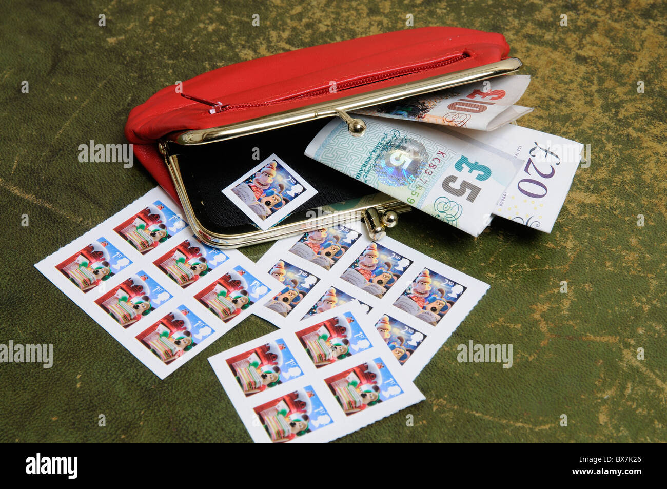 Cash in a red leather purse with Christmas theme British postage stamps Stock Photo