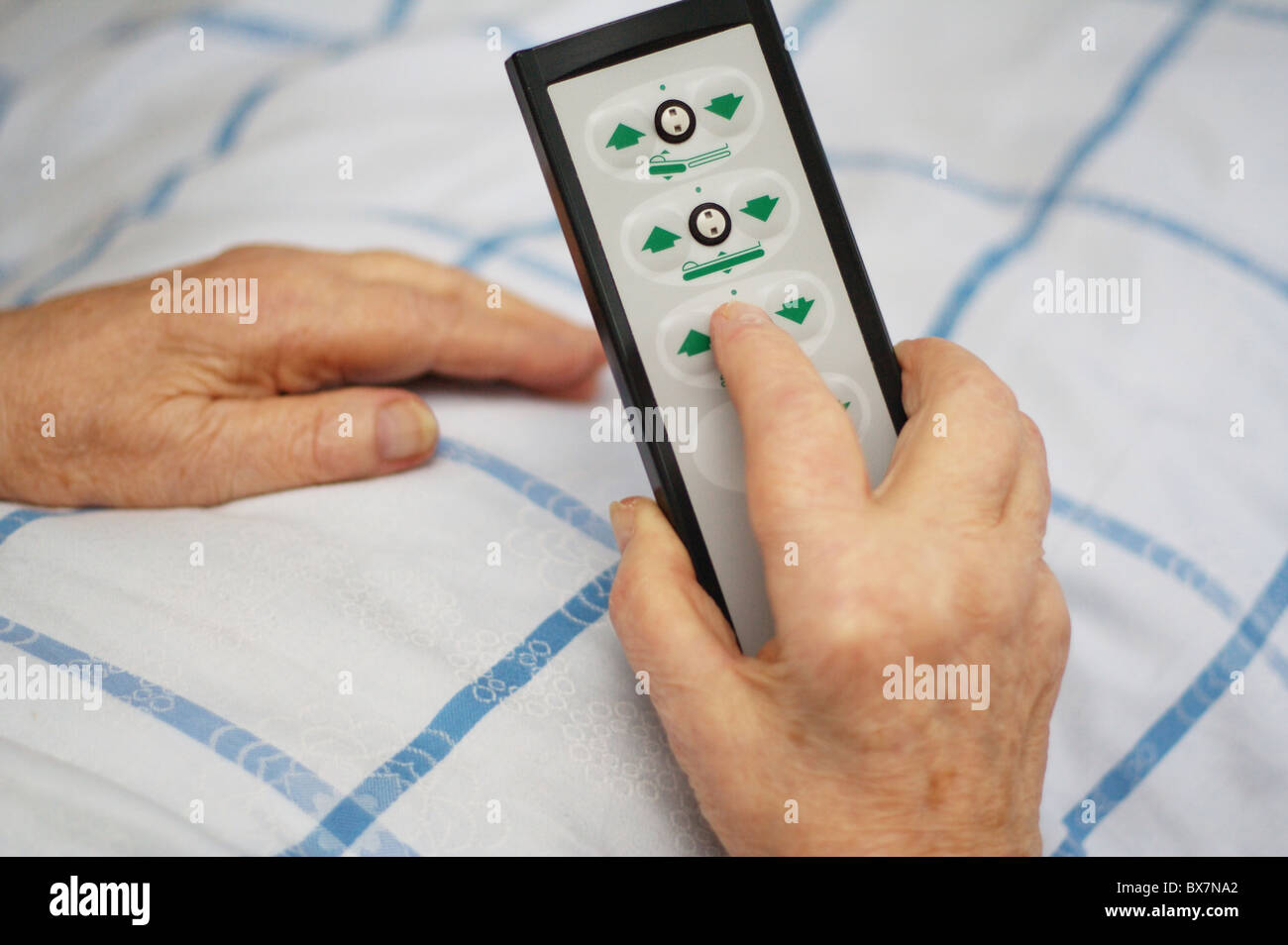 Hands of a care-dependent person holding remote control of an adjustable bed Stock Photo
