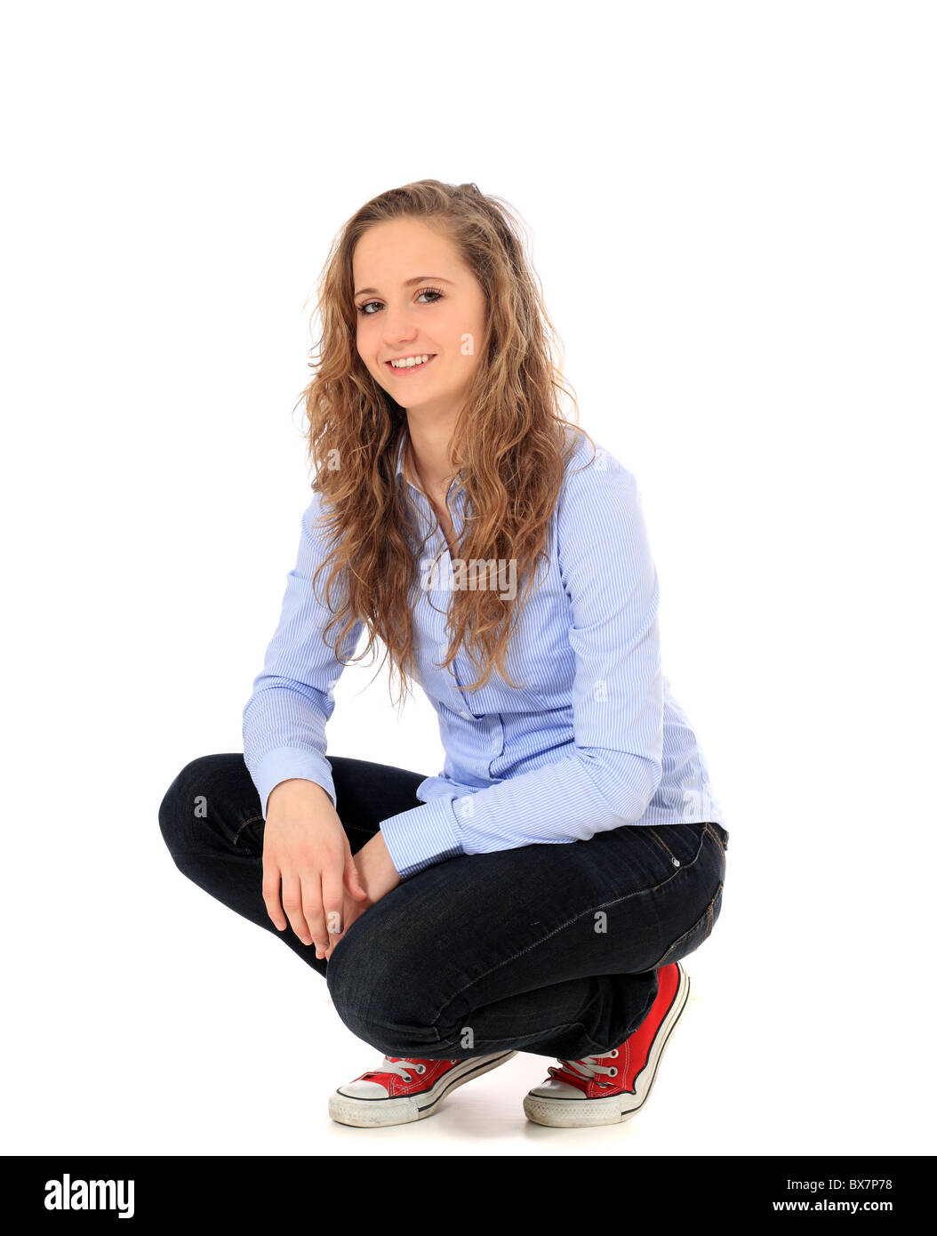 Attractive young girl in squatting position. All on white background ...