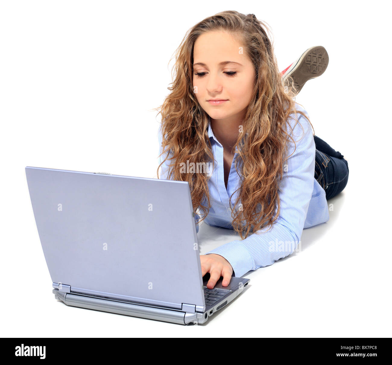Attractive young girl lying on floor using notebook computer. All on white background. Stock Photo