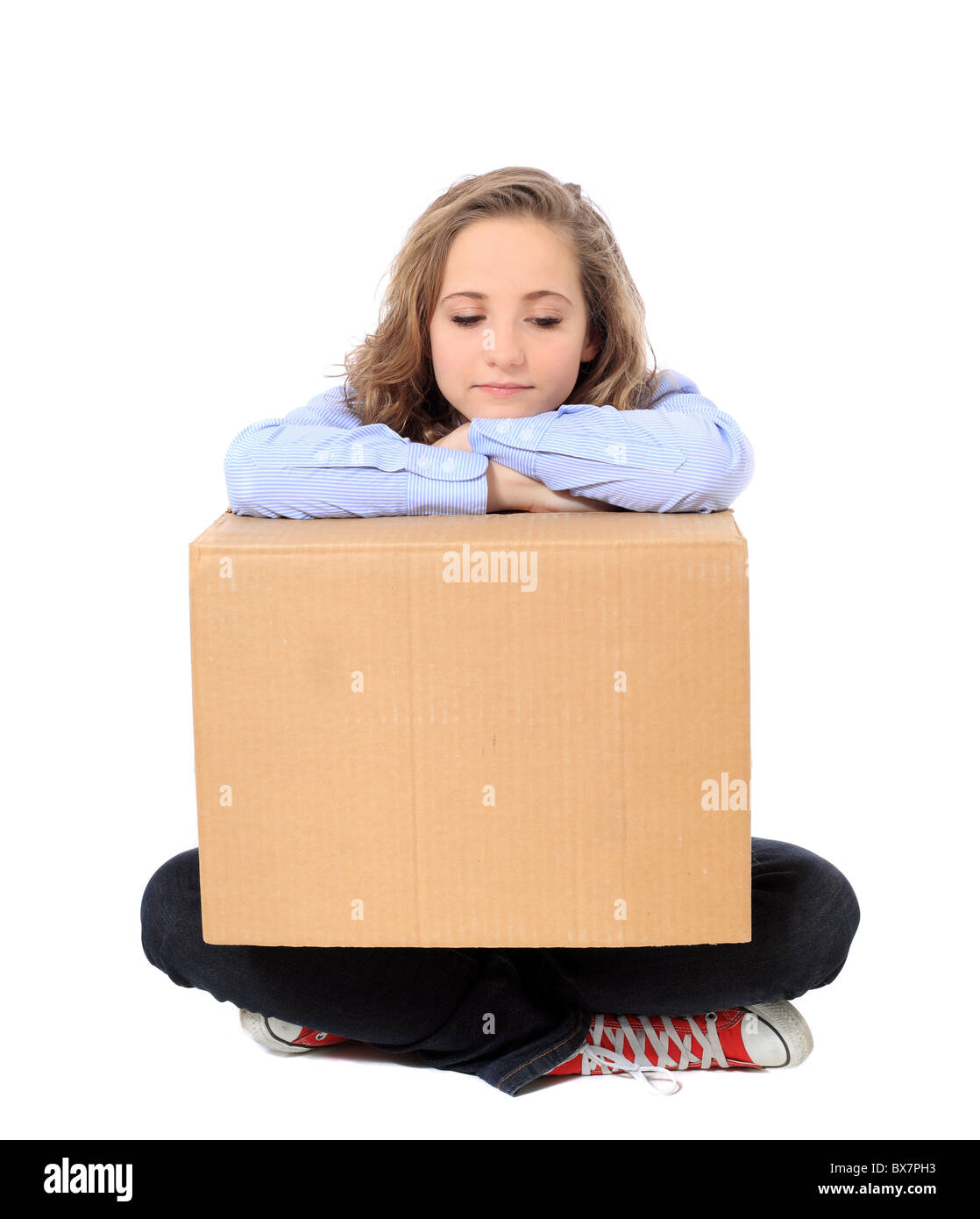 Exhausted young girl sitting on floor holding moving box. All on white background. Stock Photo