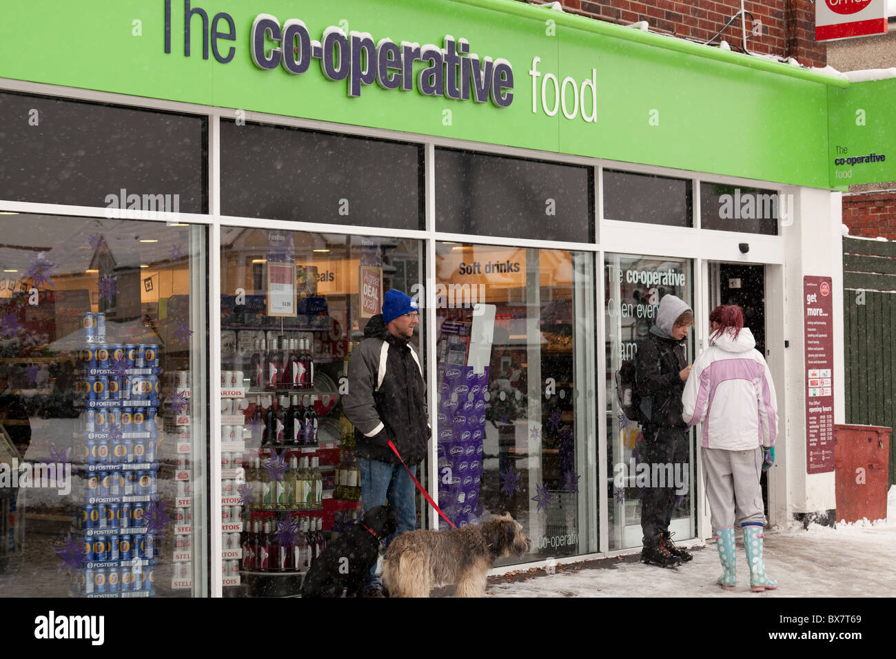 shoppers using Co-op   local shops in snow covered village Stock Photo