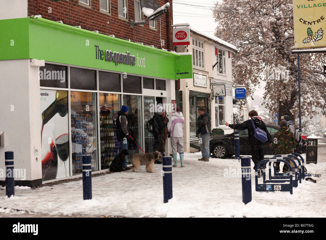 shoppers using Co-op   local shops in snow covered village Stock Photo