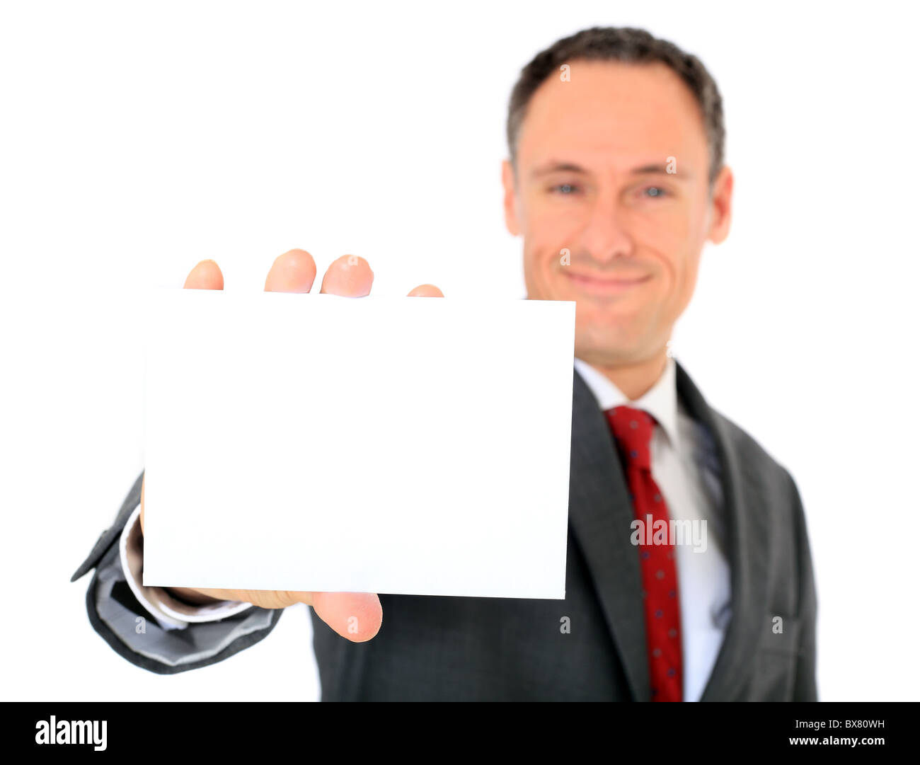Attractive businessman holding blank white card. Focus on card in foreground. All on white background. Stock Photo