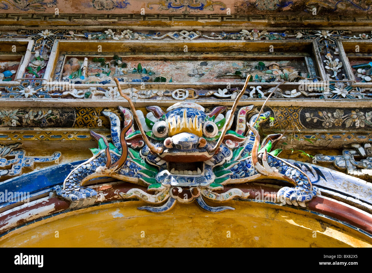 Dragon sculpture looks down from Hue citadel city gate wall Stock Photo