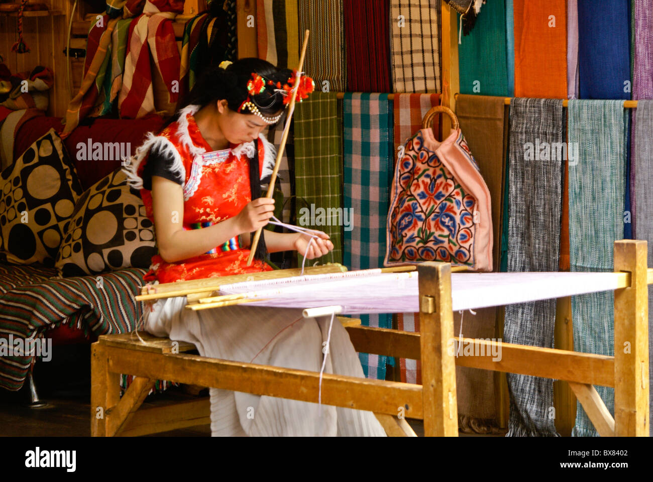 Young woman weaving in textile shop, Lijiang, Yunnan, China Stock Photo