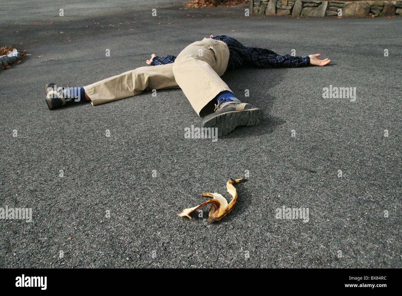 a man who had an accident when he slipped on a banana peel lies on the ground Stock Photo
