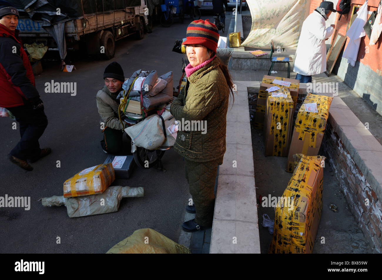 Couriers of local Shentong Express get packages on a motor tricycle to be delivered at a sub-station in Beijing, China. 2010 Stock Photo