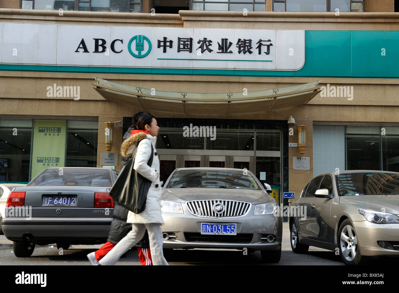 Young couple walk past a branch of the Agricultural Bank of China in Beijing, China.12-Dec-2010 Stock Photo