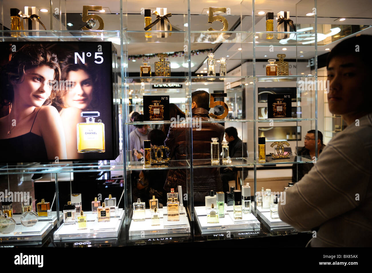 Chinese men buying or waiting at Chanel perfume stand in a shopping mall in Beijing, China. 12-Dec-2010 Stock Photo
