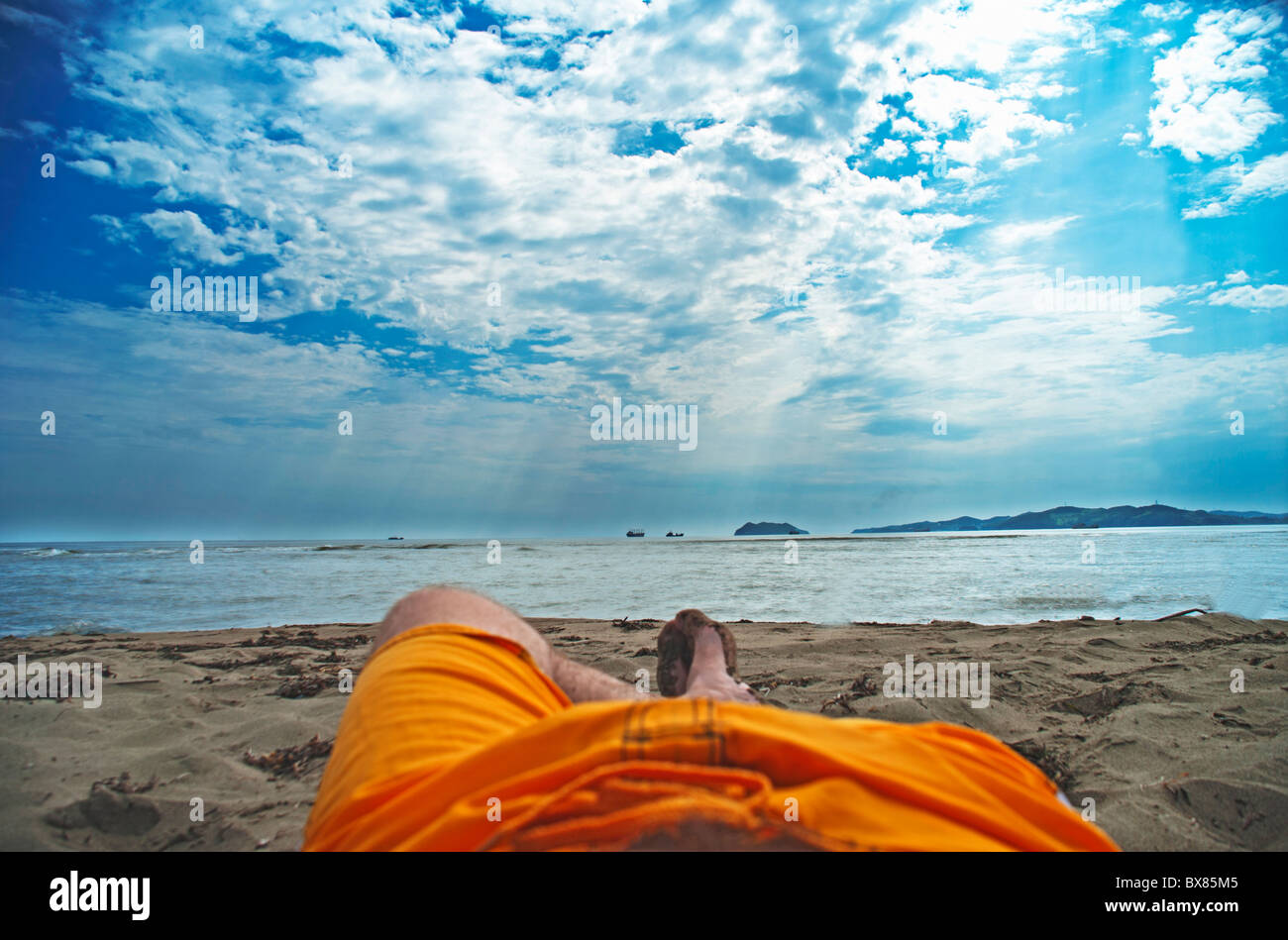 The man lies on a beach and looks at the solar sky Stock Photo - Alamy