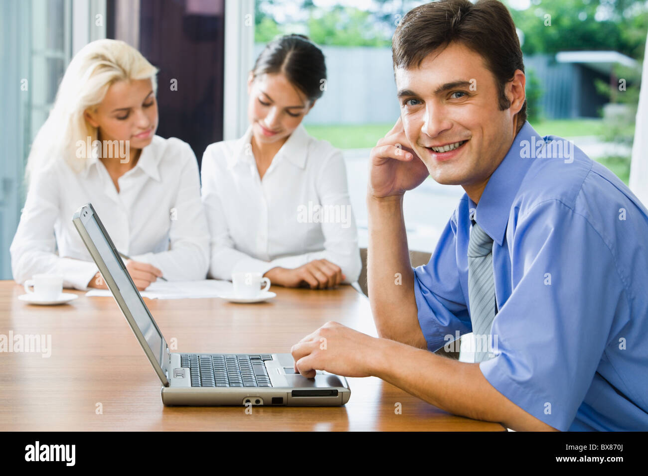 Portrait of successful young smiling businessman looking at camera in ...