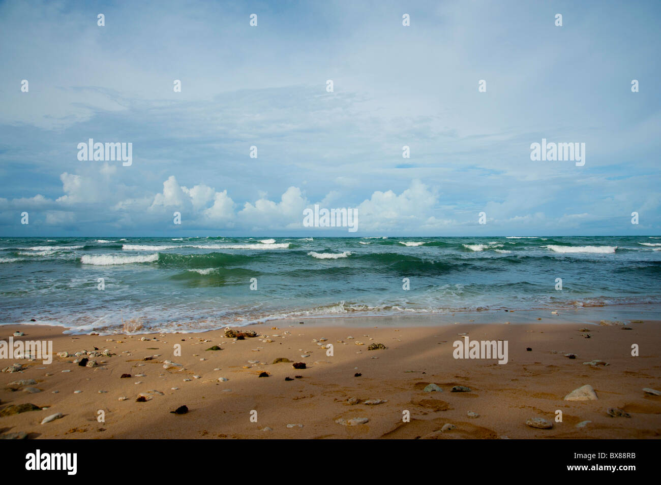 Waves gently breaking on the beach in Barbados with clouds in the distance Stock Photo