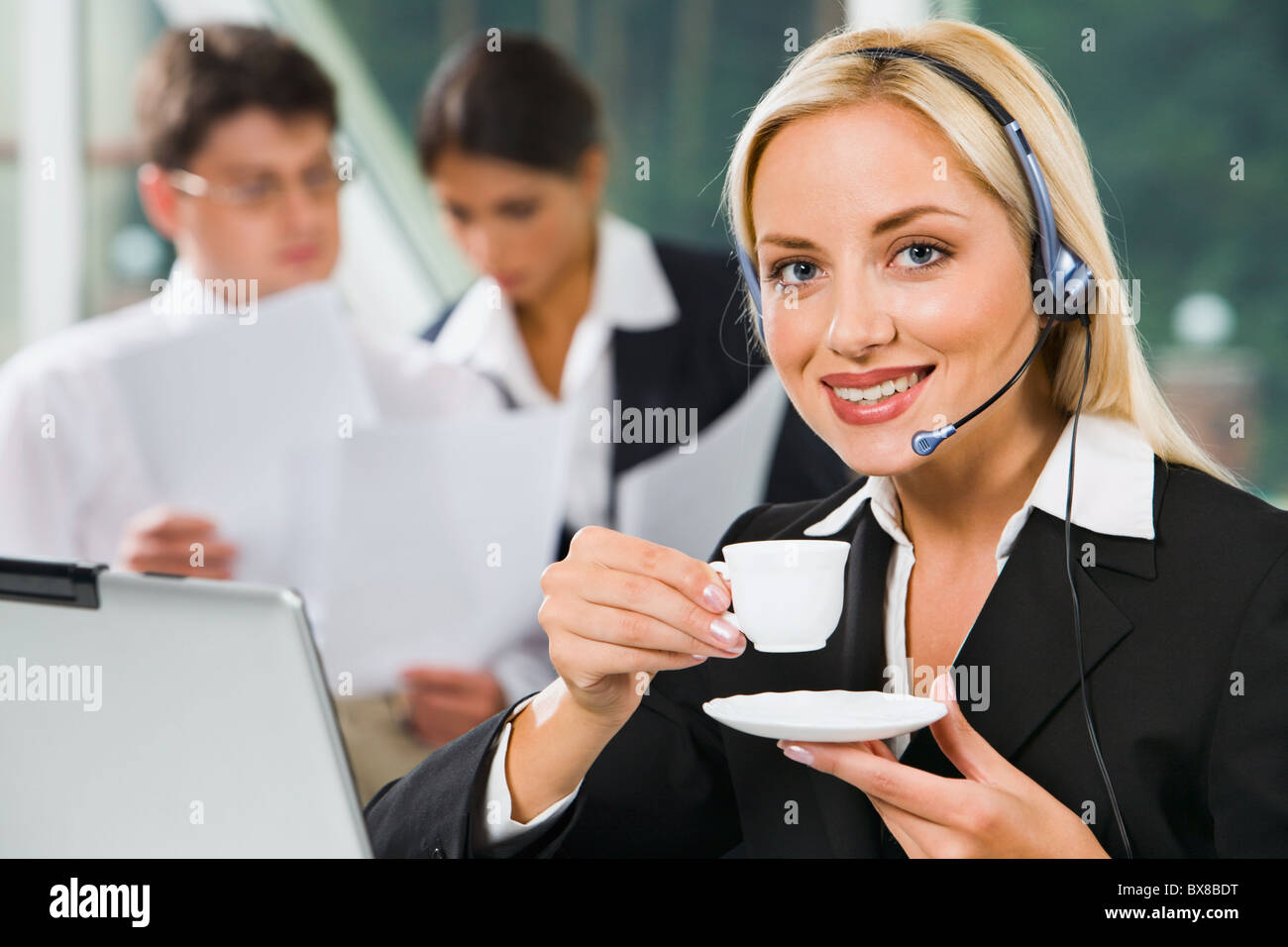 Portrait of smiling businesswoman with headset looking at camera and ...
