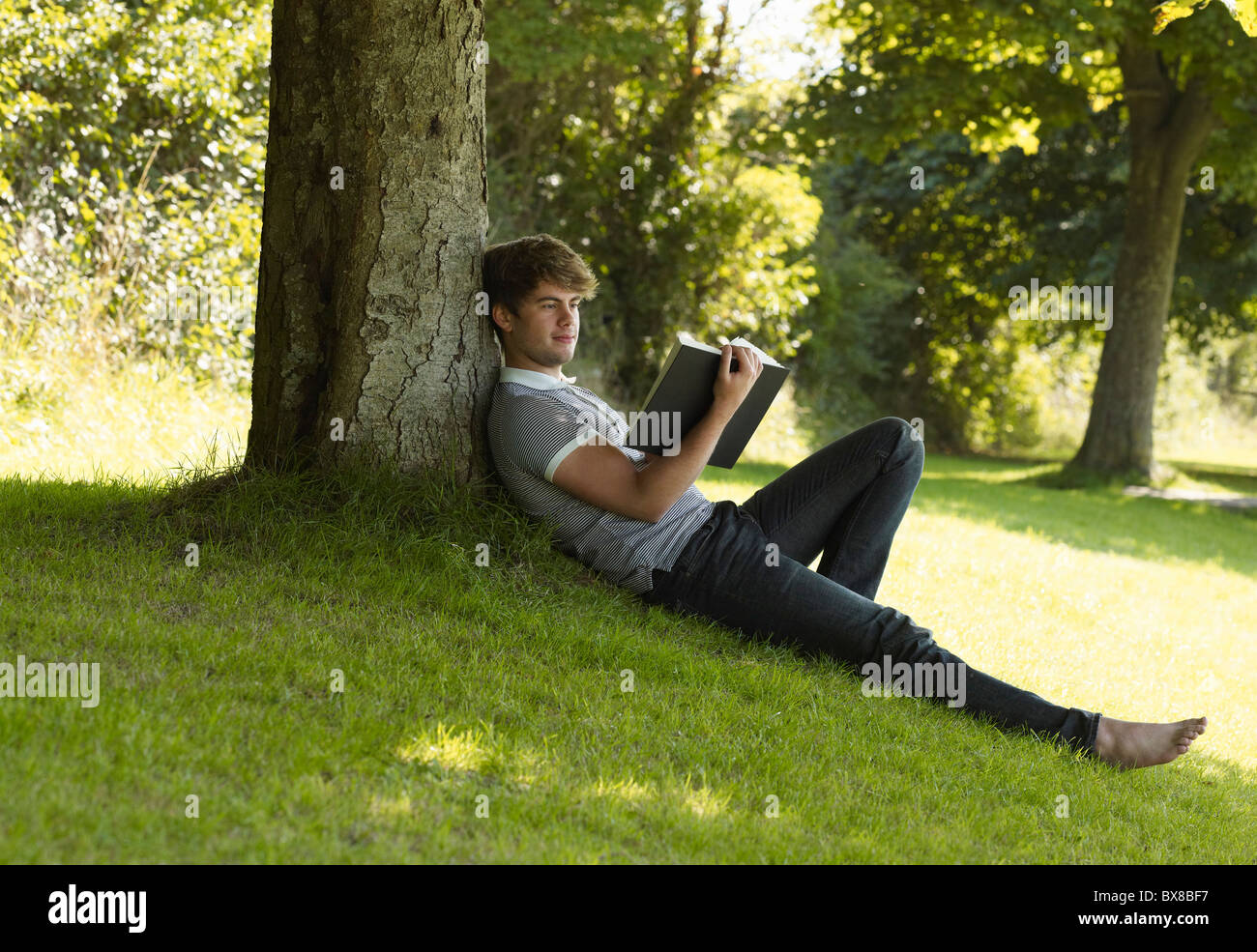 человек на траве. человек сидит на дереве. парень сидит на дереве. фотосессия на природе. сидит под деревом.