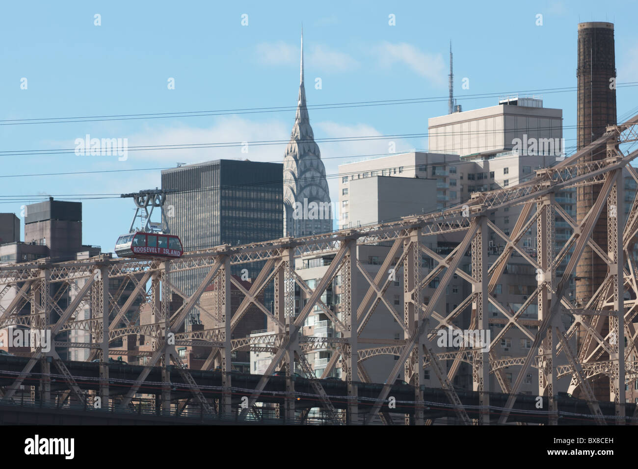 The Roosevelt Island Tram crosses the East River with the Queensboro Bridge and Manhattan skyline in the background in New York City. Stock Photo