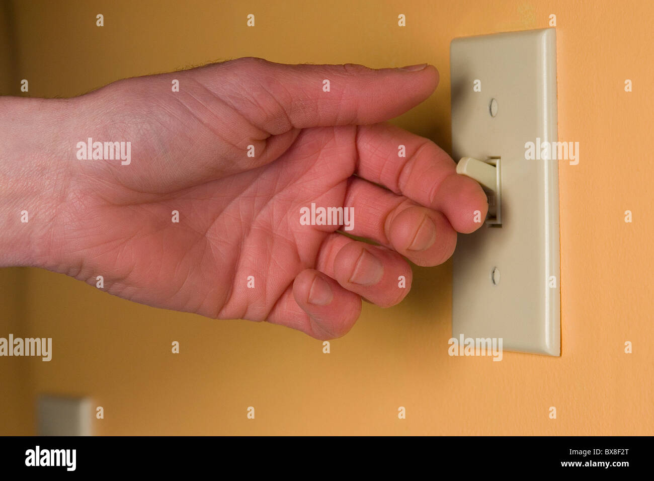 Hand turning on a light switch Stock Photo