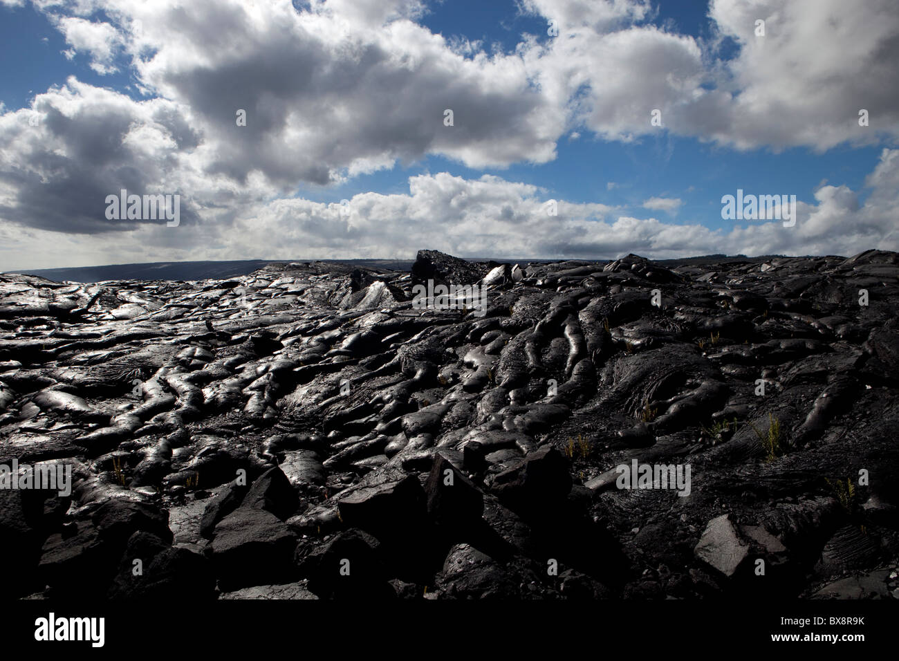 Black lava formation with blue sky above and white clouds in Hawaii Big Island Stock Photo