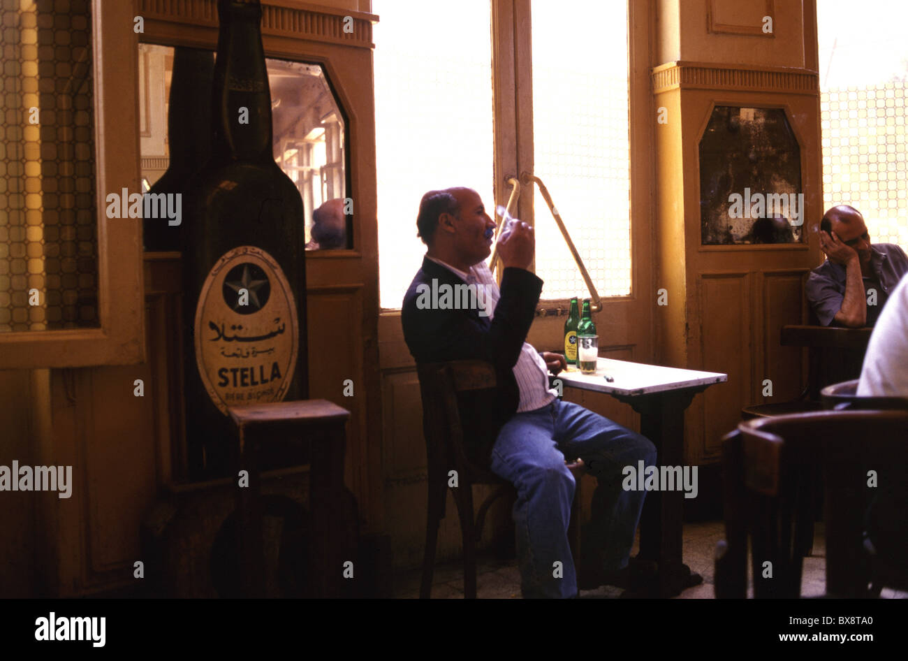 Egyptian men smoke and drink local Stella Beer inside Cafe Riche in downtown Cairo Egypt Stock Photo