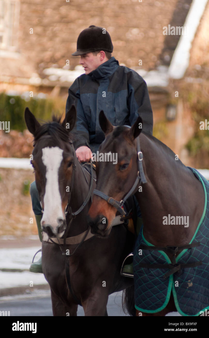 A local rider with two horses in the Cotswold village of Broadway in Worcestershire, England. Stock Photo