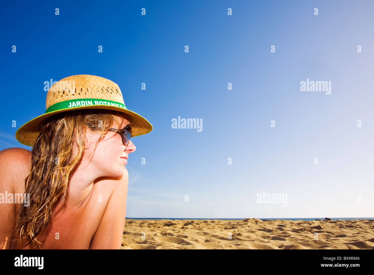 Woman on the beach with a straw hat at sunset Stock Photo - Alamy