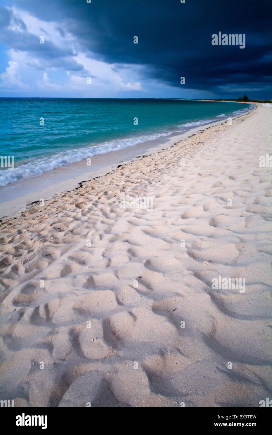 White sand beach and beautiful waters under an ominous stormy sky at ...