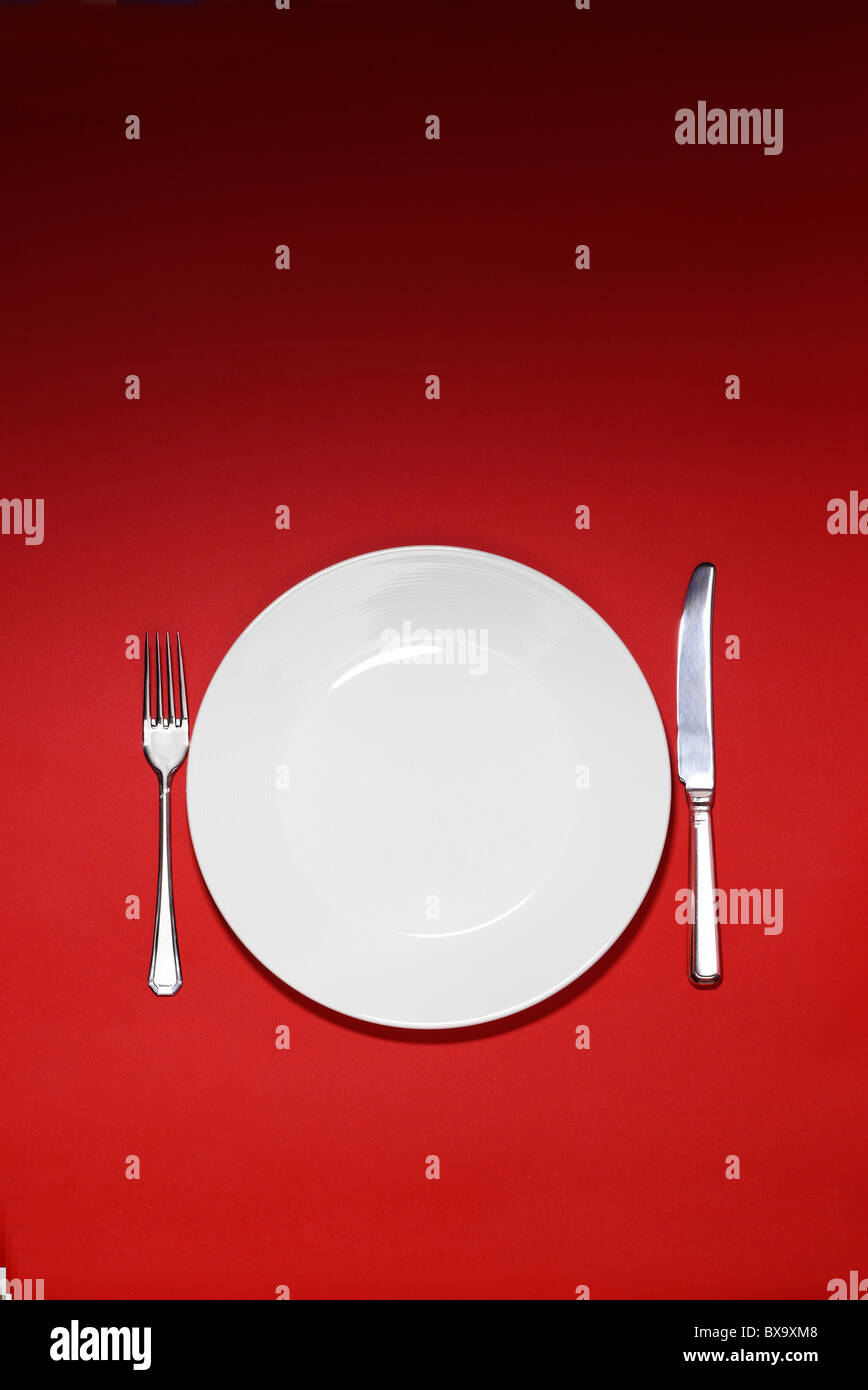 White plate and place setting on a red background Stock Photo