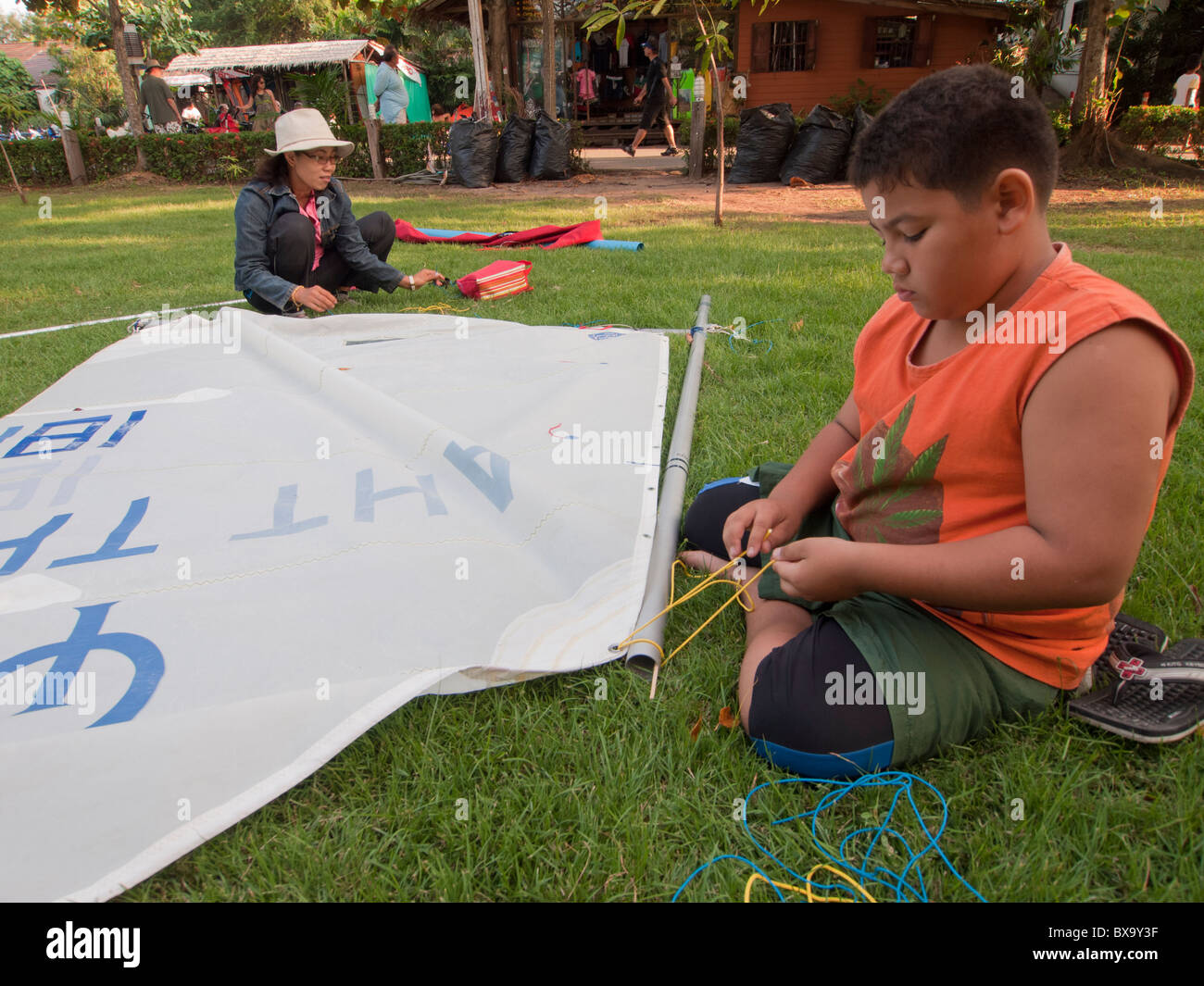 The boy and his mother rigging the optimist sail up together. Stock Photo