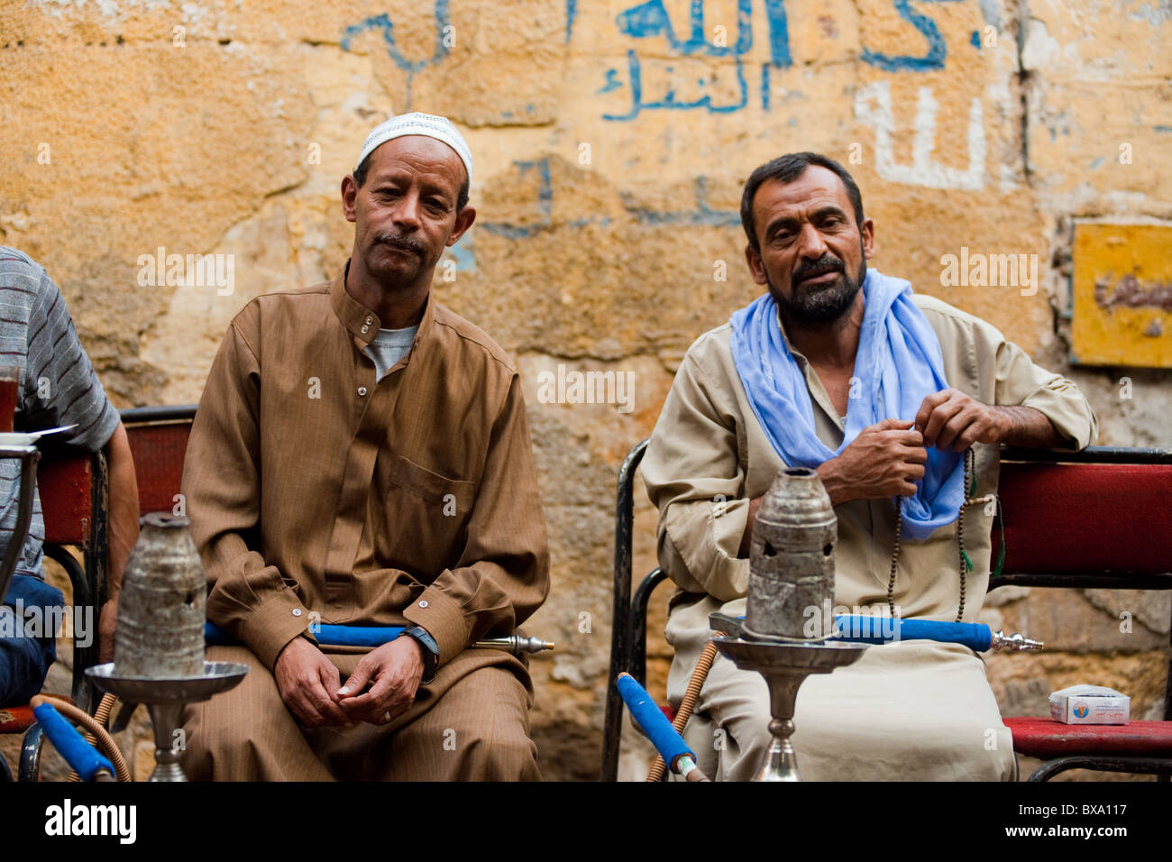 Two Egyptian men enjoying smoking shisha at a traditional outdoor street cafe in daily life of Islamic Cairo Stock Photo