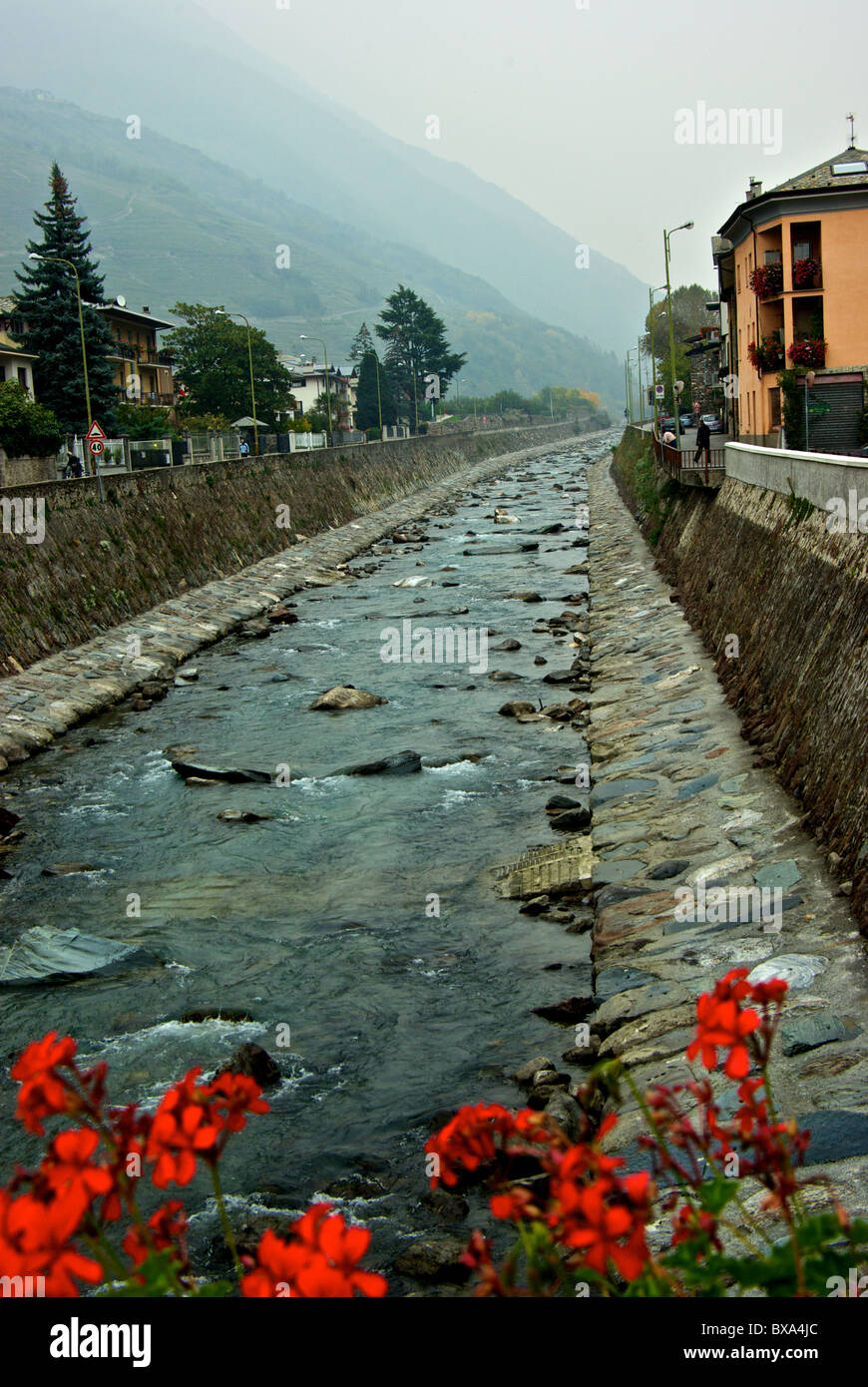 Adda River contained by stone masonry dikes flowing through village of Tirano Italy Stock Photo
