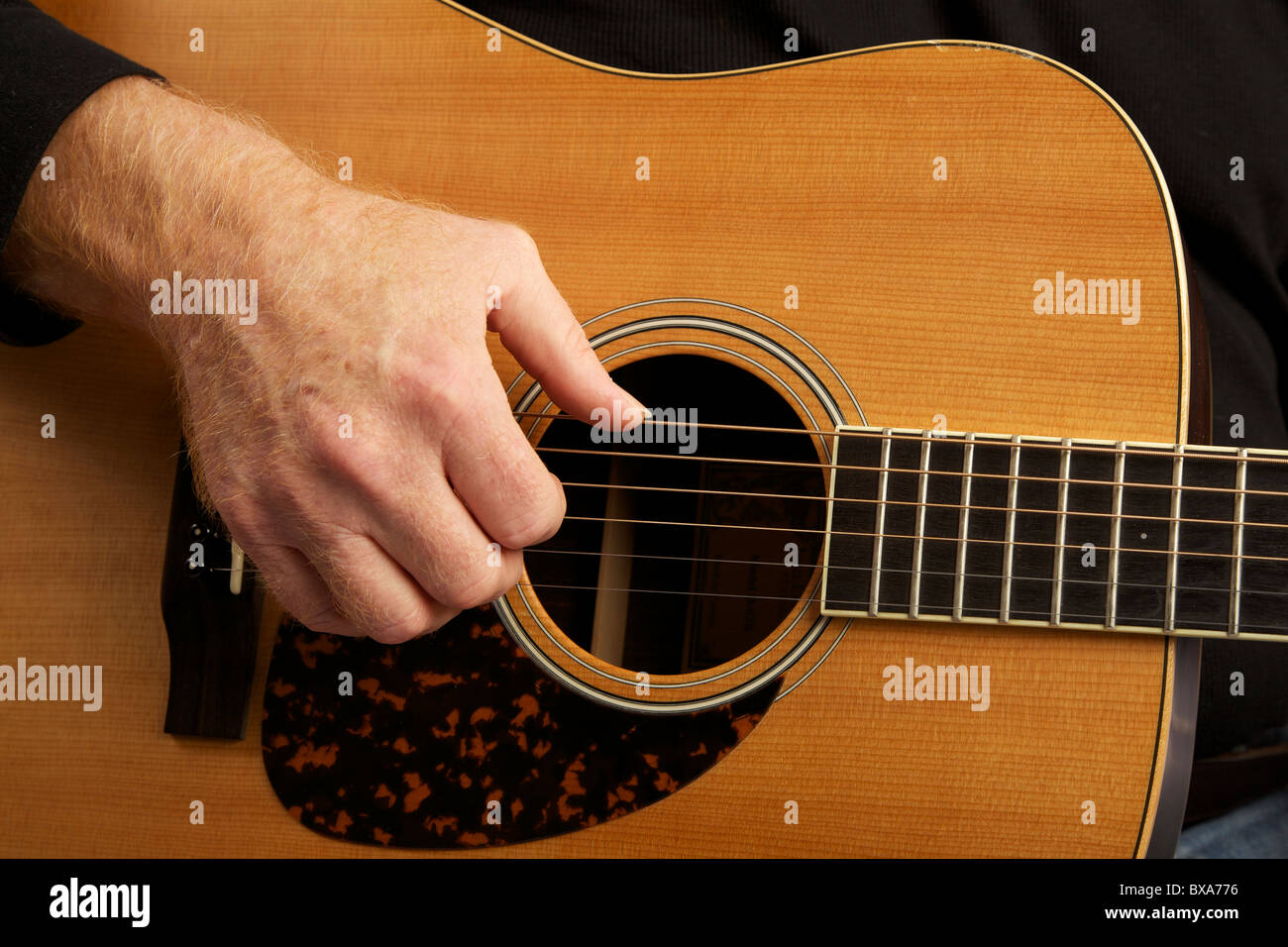 Man playing guitar. Close up of right hand and sound box. Stock Photo