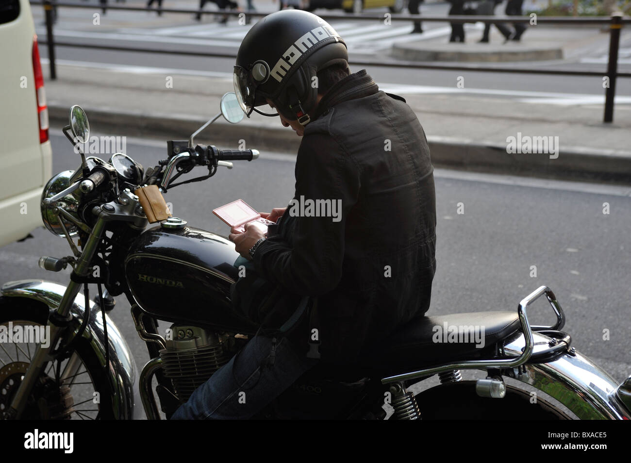 Young Japanese man playing Nintendo on motorcycle in Akihabara, Tokyo, Japan Stock Photo