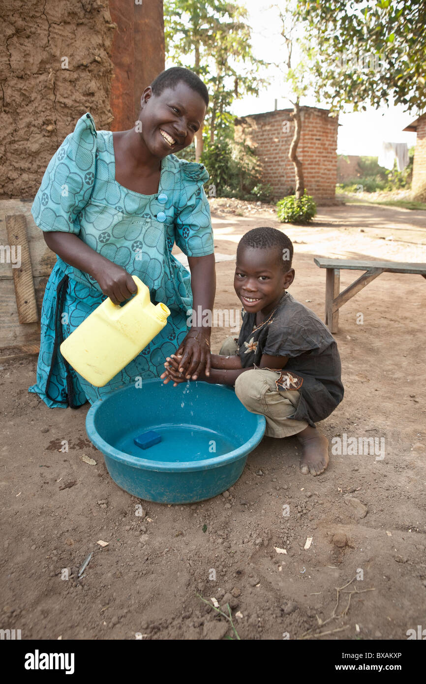 Ms. Rose Takuwa (left) teaches her son Godwin (5) hand washing in Iganga, Eastern Uganda. Stock Photo