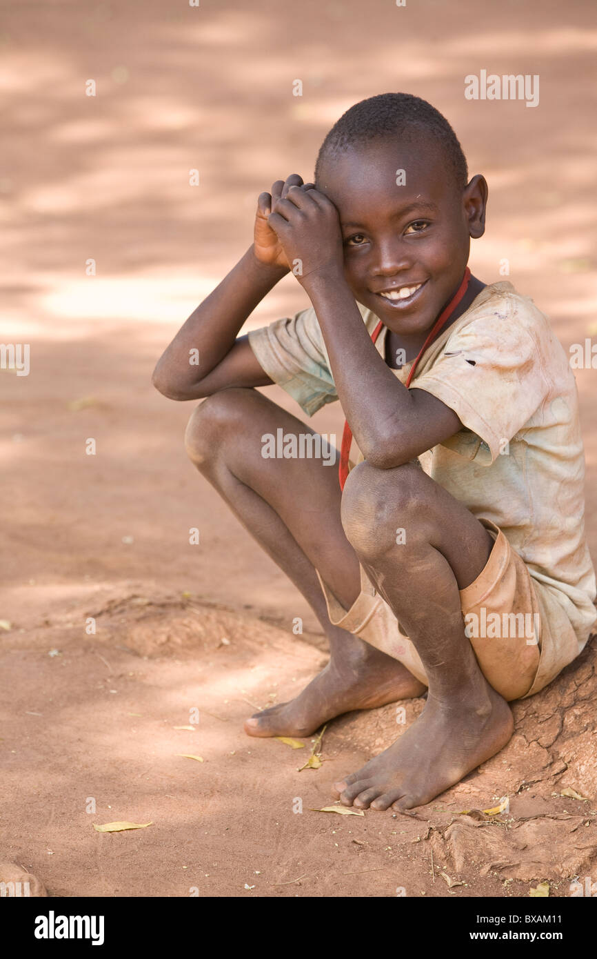 A young barefoot boy smiles in Bulowooza Village, Iganga District, Eastern Uganda, East Africa. Stock Photo