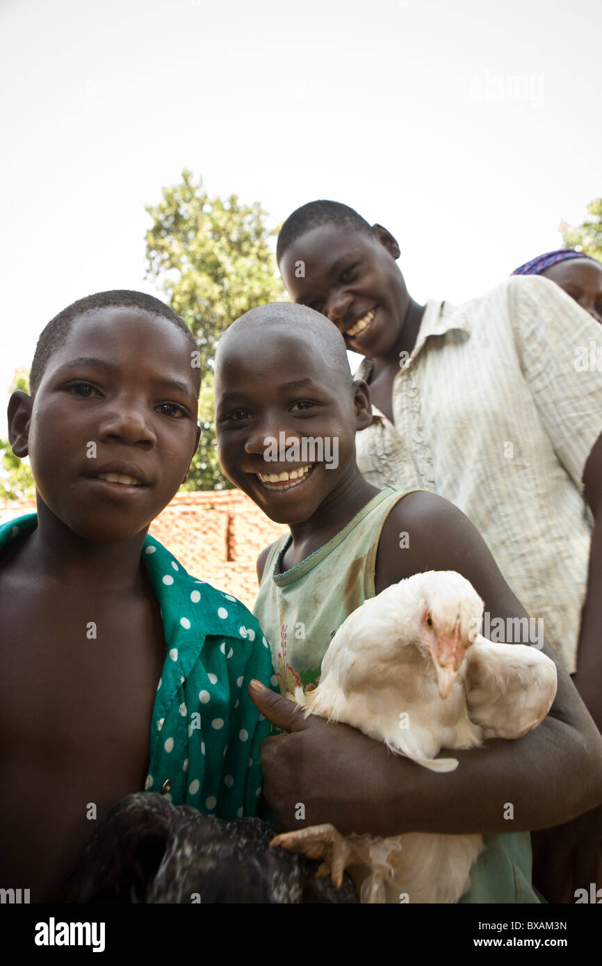 Children bring their chickens to a community vaccination day in Nampikika Village, Iganga District, Eastern Uganda, East Africa. Stock Photo