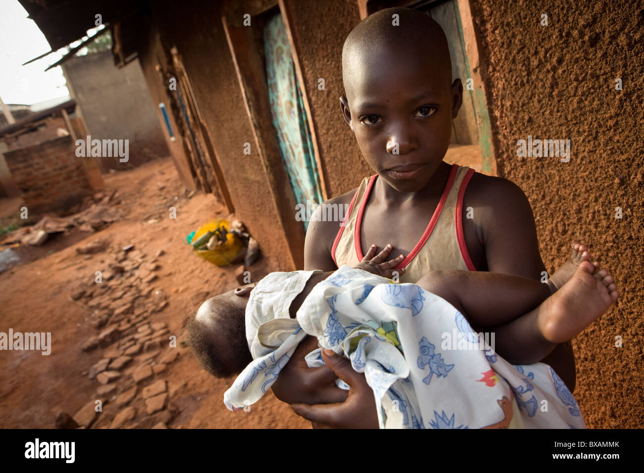 A young boy holds an infant in a slum in Jinja, Uganda, East Africa. Stock Photo