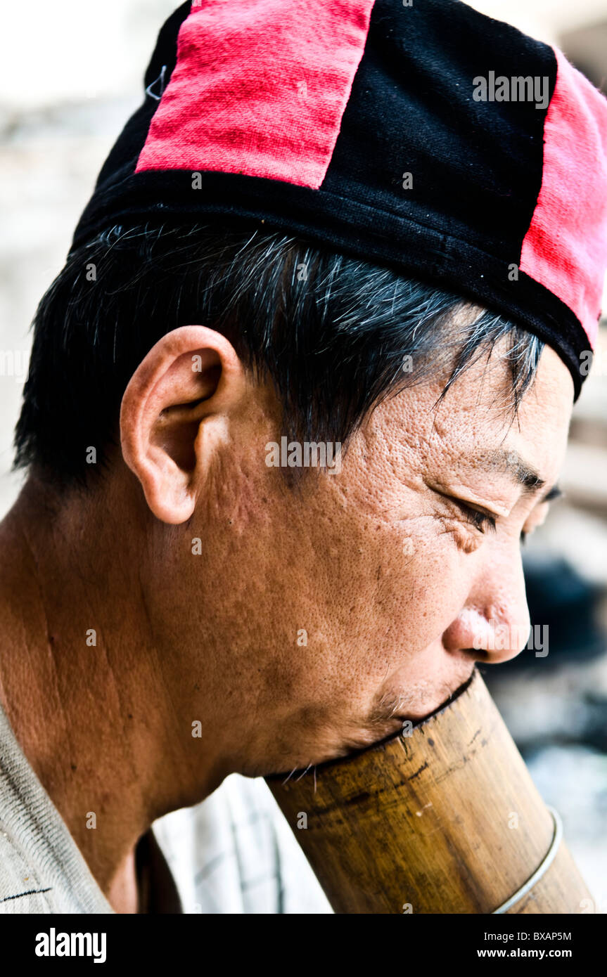 A Yao man smoking tobacco with a traditional bamboo pipe.. Stock Photo