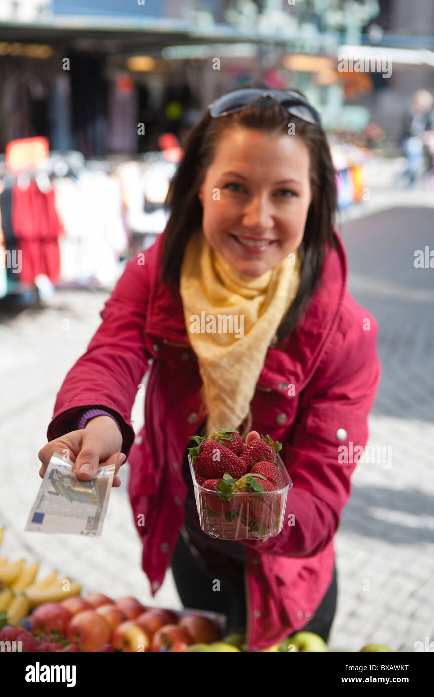 Young woman paying for basket of strawberries Stock Photo