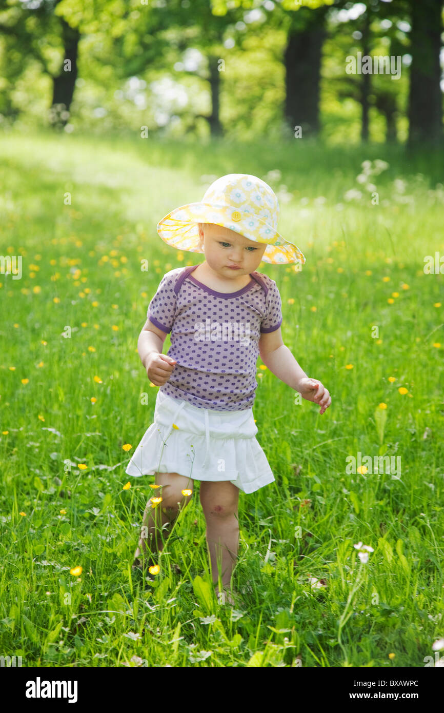 Girl wearing sun hat walking through meadow Stock Photo