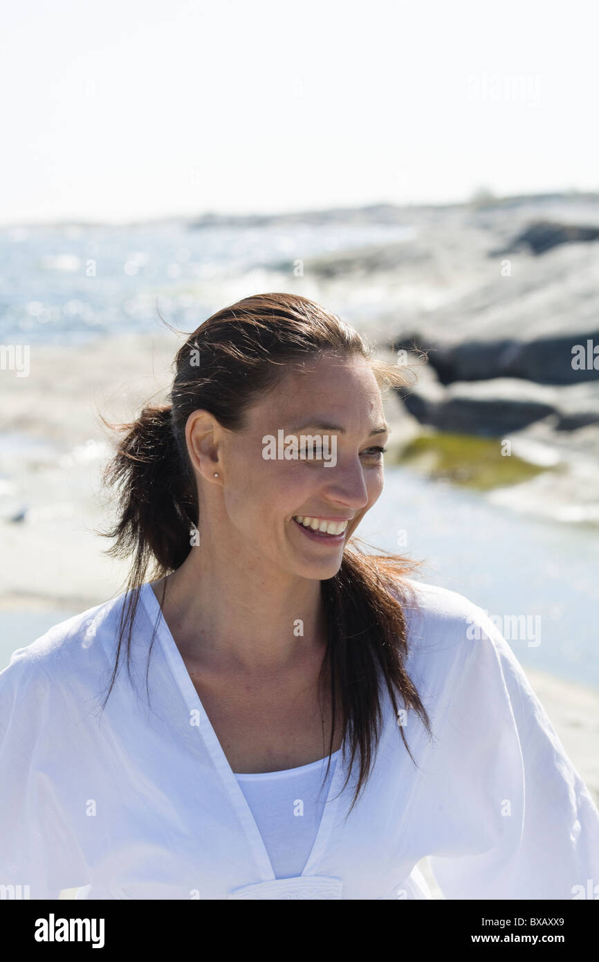 Woman standing and smiling in front of sea Stock Photo - Alamy
