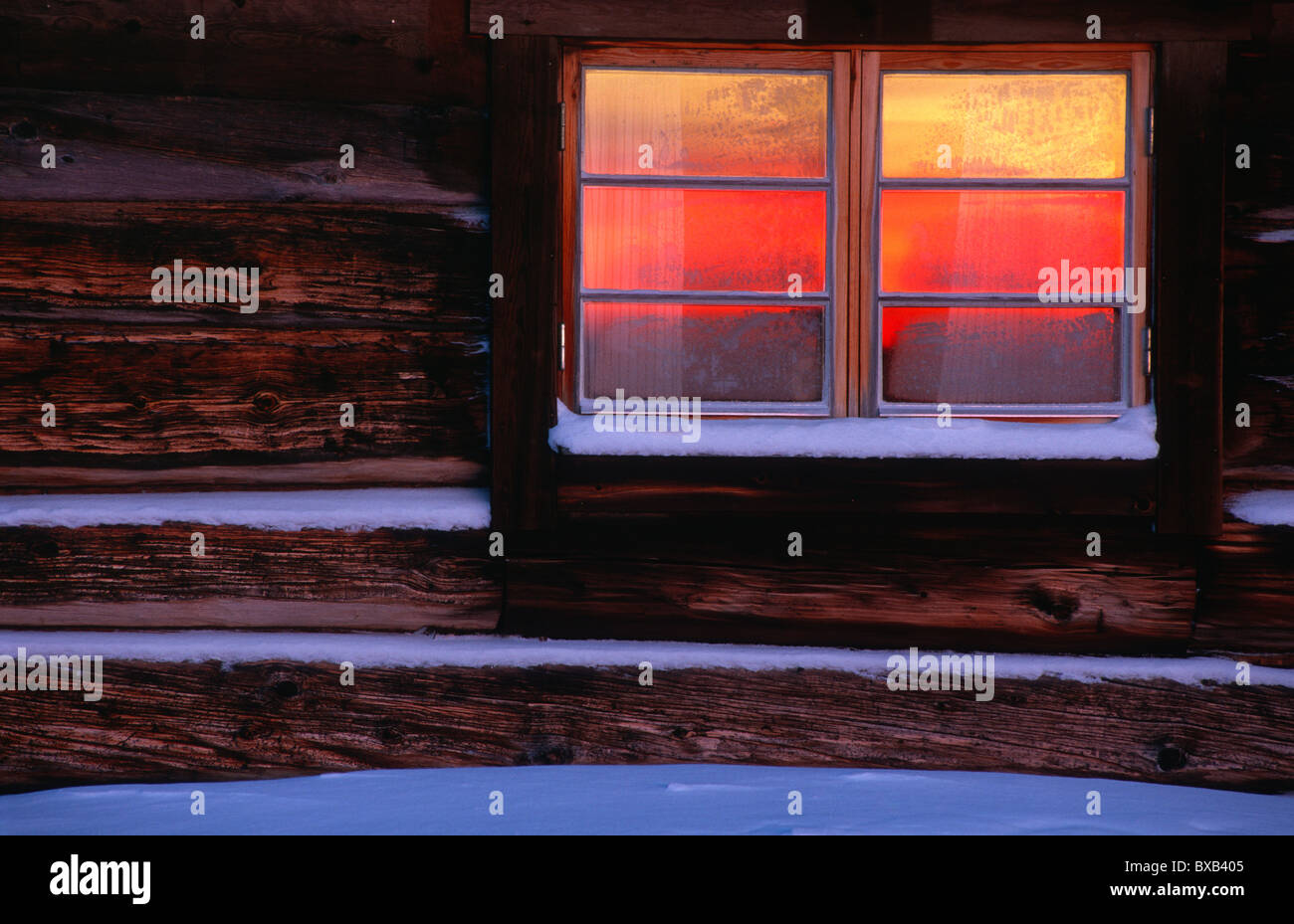 Warm light in log cabin window Stock Photo