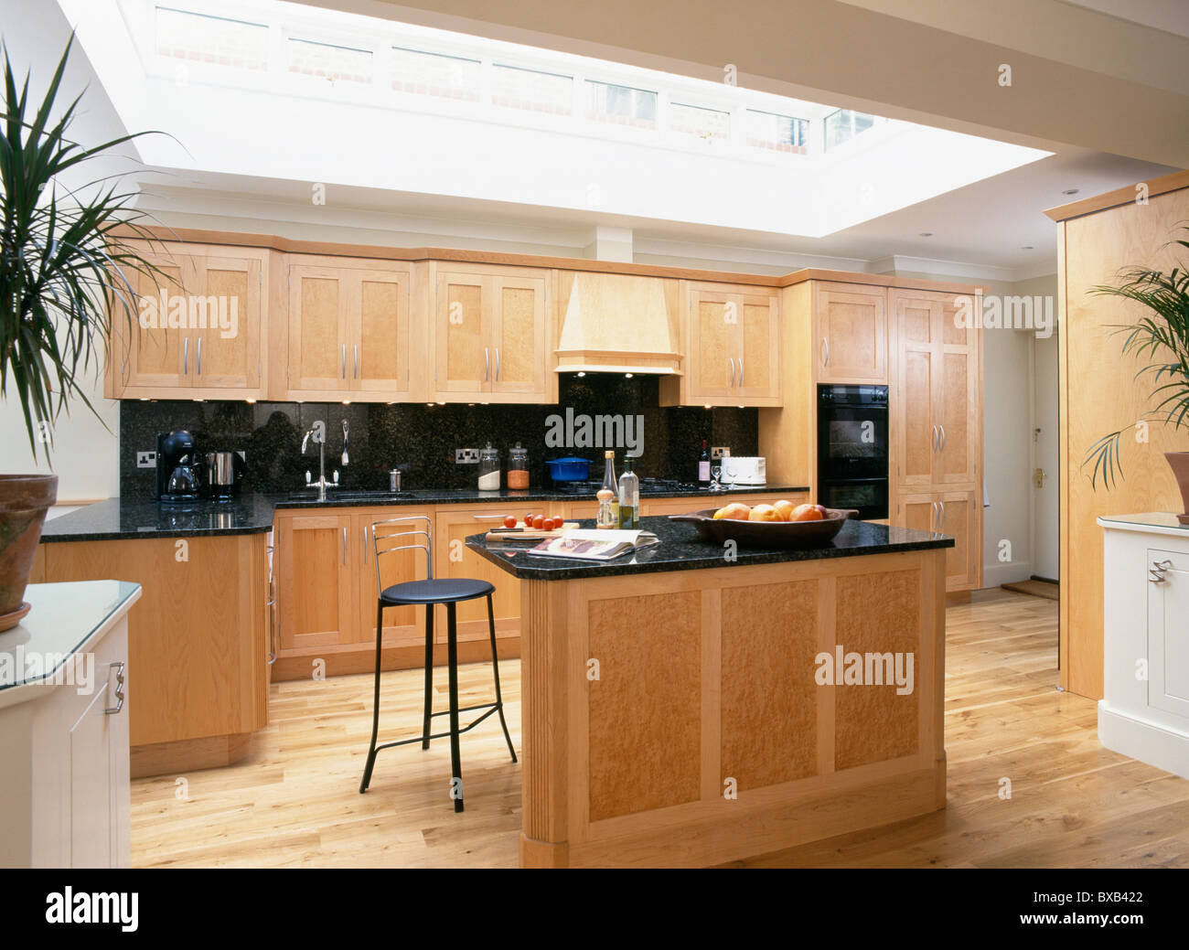 Stool at breakfast bar on island unit with black granite worktop in